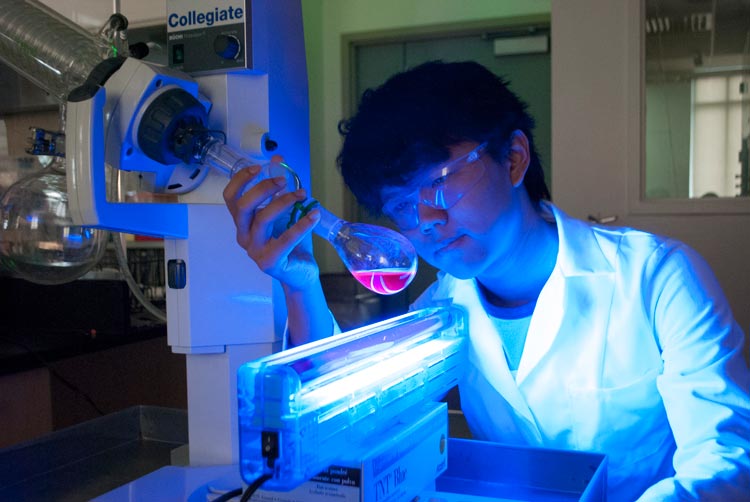 Student holding a scientific instrument inside a lab